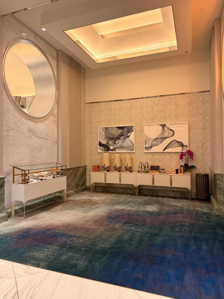 Elegant lobby area with modern decor, featuring a decorative rug, beverage station, and wall art.